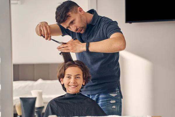 Jovem cuidadosamente segurando e cortando o cabelo — Fotografia de Stock