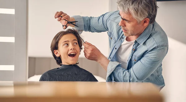 Homem idoso mudando penteado de menino pequeno — Fotografia de Stock