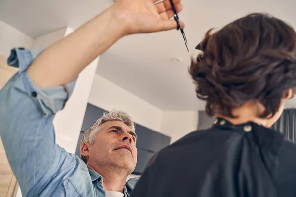 Homem olhando para cima tentando cortar o cabelo — Fotografia de Stock