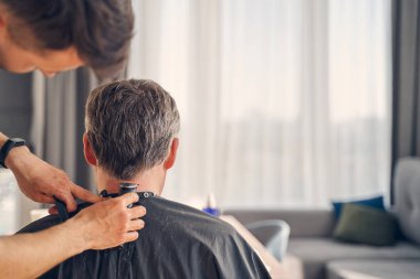 Esmer erkek özel ekipmanla saç kesiyor.