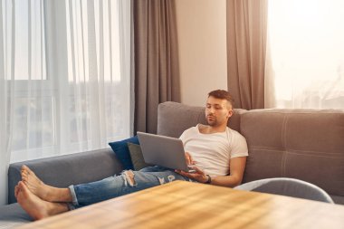 Yakışıklı genç erkek rahat bir şekilde yatıyor ve çalışıyor.