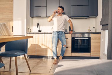 Yakışıklı, beyaz bir adam telefonda konuşuyor.