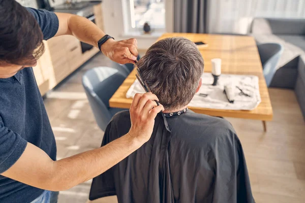 Hombre sentado frente a la mesa y recibiendo un nuevo corte de pelo — Foto de Stock