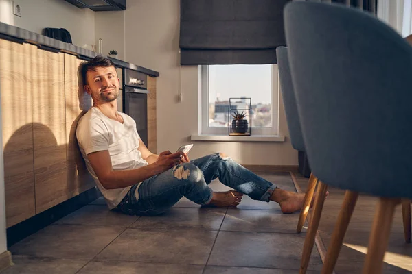 Hombre guapo sentado en el suelo en casa — Foto de Stock