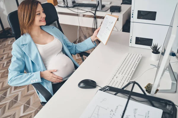 Mujer embarazada alegre que trabaja en la oficina moderna — Foto de Stock