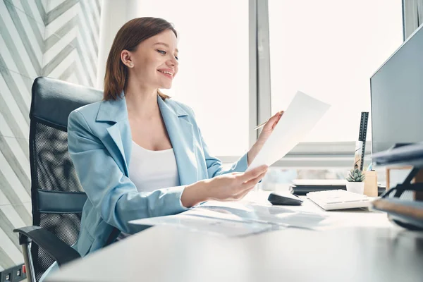 Hermosa joven sentada a la mesa en el trabajo — Foto de Stock