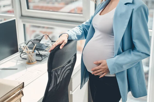 Young pregnant woman standing by office chair — Stock Photo, Image