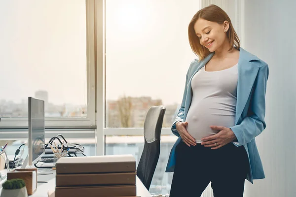Glädjande gravid kvinna står i moderna kontor — Stockfoto