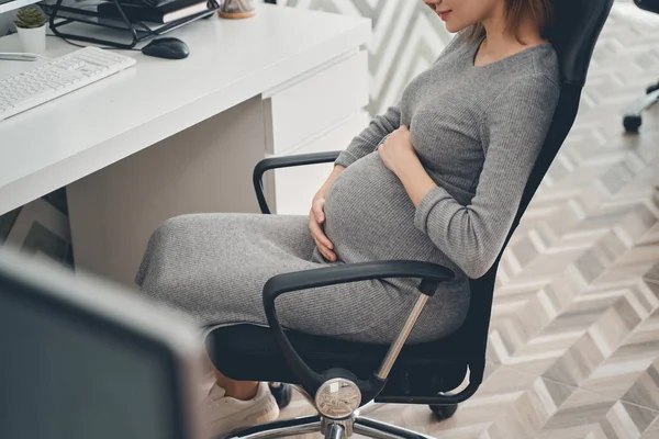 迷人的孕妇在工作时坐在桌旁 — 图库照片