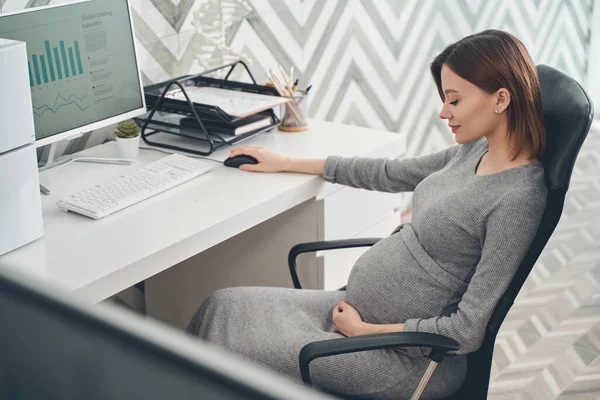 Leende gravid kvinna som sitter vid bordet på jobbet — Stockfoto