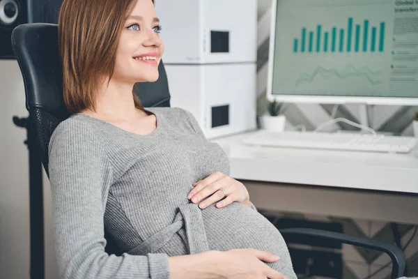 Весела вагітна леді сидить в офісному кріслі на роботі — стокове фото