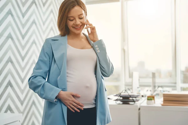 Charming pregnant woman talking on cellphone at work — Stock Photo, Image
