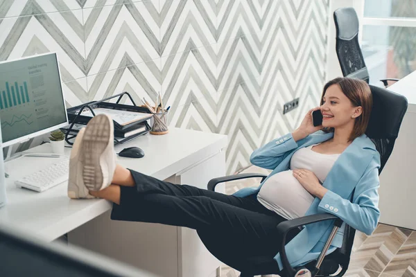 Charming pregnant lady talking on mobile phone at work — Stock Photo, Image