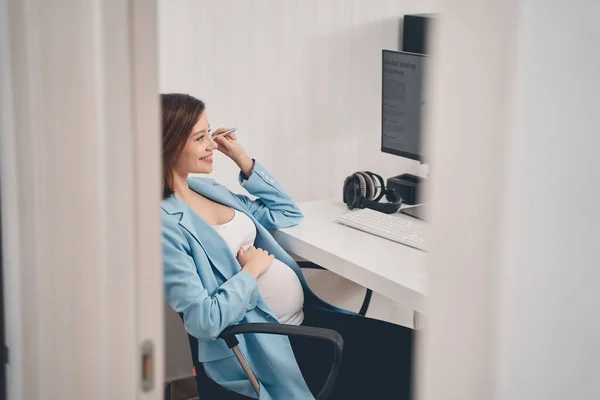 Vacker gravid dam sitter vid skrivbordet på kontoret — Stockfoto