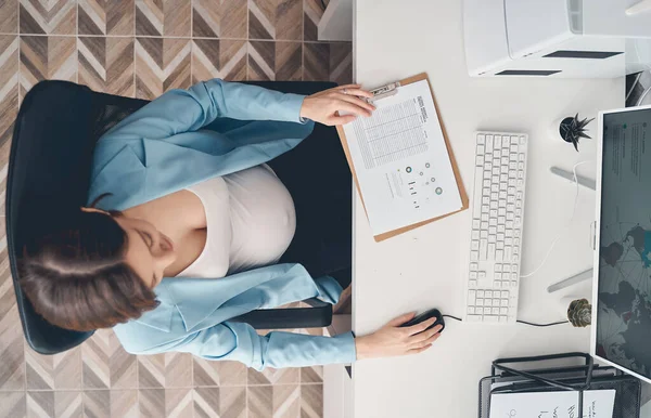 Elegante zwangere dame zit aan tafel met computer aan het werk — Stockfoto
