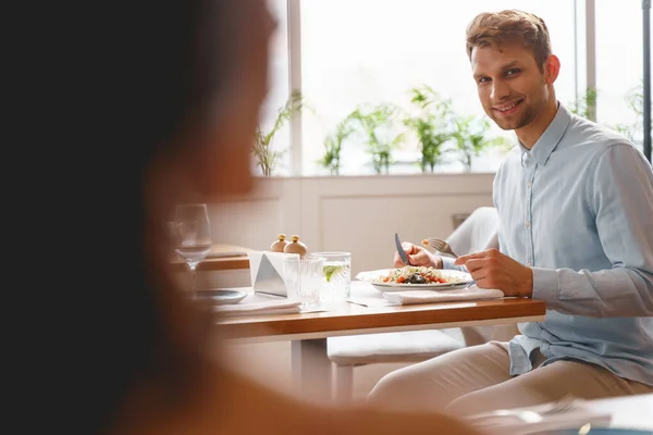 Vreugdevolle jongeman op zoek naar dame in cafe — Stockfoto