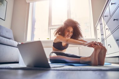 Kıvırcık saçlı mutlu kız esneme egzersizleri yapıyor.