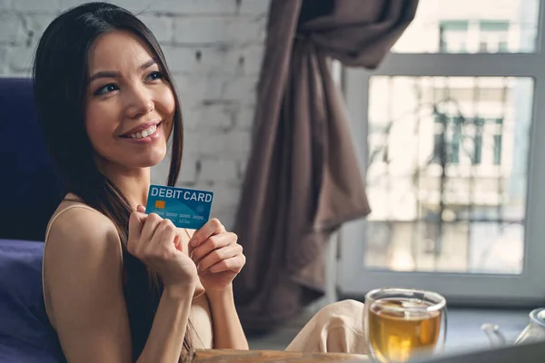 Hermosa mujer joven sosteniendo tarjeta de débito y sonriendo — Foto de Stock