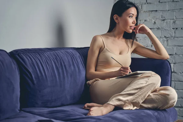 Красивая молодая женщина сидит дома на диване — стоковое фото