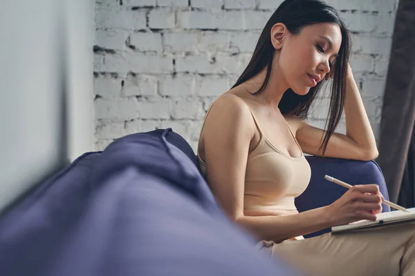 Bella giovane donna che disegna nel quaderno a casa — Foto Stock