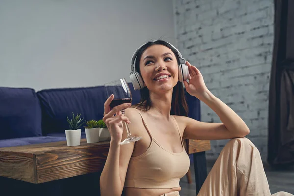 Cheerful young woman listening to music through wireless headphones — Stock Photo, Image