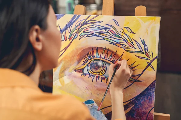 Young woman painting eye on easel in home art studio — Stock Photo, Image