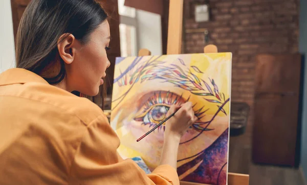 Hermosa joven mujer pintando ojo en caballete en casa — Foto de Stock