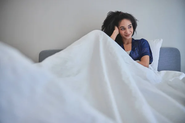 Jovem alegre sentada debaixo do cobertor — Fotografia de Stock