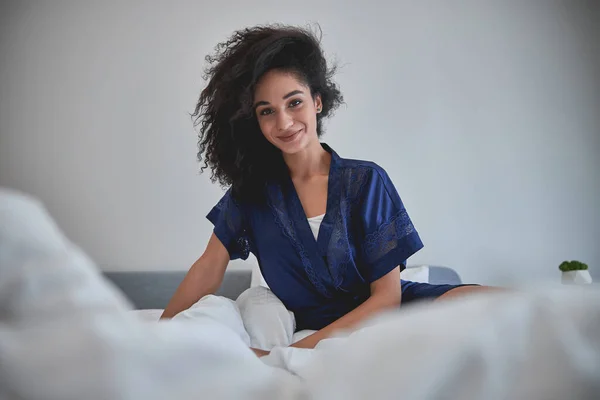 Fröhliche junge Frau sitzt auf ihrem Bett — Stockfoto