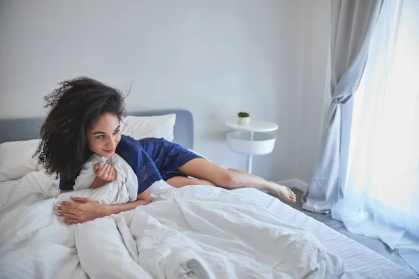 Kényeztetett barna nő fekszik az ágyon — Stock Fotó