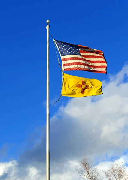 Amerikaanse en New Mexico vlaggen op stok met blauwe lucht en de wolken — Stockfoto