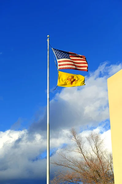 American and New Mexico Flags on pole with blue sky and clouds — Stock Photo, Image