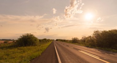 Brezilya ve uruguay sınırındaki otoyolun, ufuktaki renklerin ve güneşin batışının görüntüsü. Brezilya 'nın güneyindeki kırsal alan.