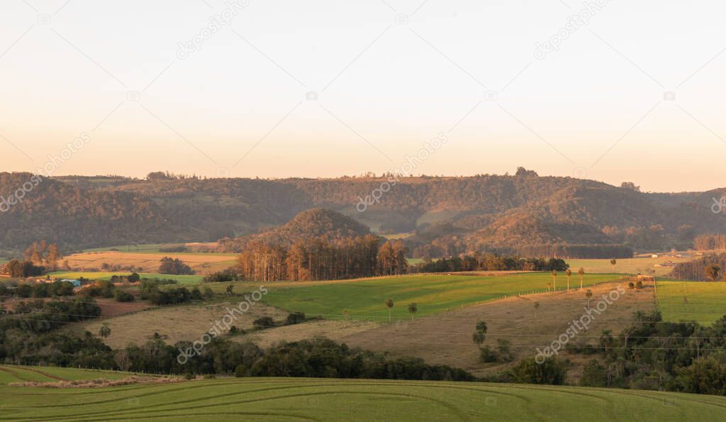 Sunset over rural landscape in Jaguari River Valley, Jaguari City, Brazil. In the background a mountain with native Brazilian trees.