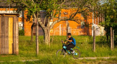 Sırtında bir sırt çantasıyla okula bisikletle giden Brezilyalı genç bir öğrenci. Küçük bir Brezilya şehrinin günlük sahnesi. Okul ve eğitim.