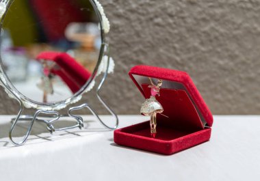 Mücevher ve mücevher. Kırmızı bir çantada bir balerin kolyesi. Görüntü aynaya yansıdı. Güzellik ve duygusallık. Lezzetli. Kadınlık ve gençlik duyguları. Moda. Biçim.