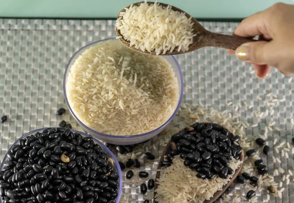 grains of rice and bean cherries mixed with a wooden spoon. Grains for human consumption. Brazilian cuisine. Cooking. Main dish of the Brazilian diet.