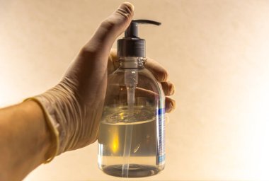 Tek kullanımlık eldiven ve alkol jeliyle. Jel alkolü, Covid-19 döneminde tüketiciler tarafından en çok aranan ürünlerden biri haline gelmiştir..