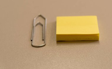 Bir ofis masası, büyük bir ataç ve üzerinde sarı bir ped. Ofis malzemeleri ve kırtasiye malzemeleri.