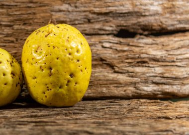 Tahta arka planda izole edilmiş sarımsı pembe guava meyveleri. Tüketim için toplanmış yeşil yapraklı taze guavalar. Brezilya 'dan tropik meyveler. Ahşap dokular. guava yaprakları ve meyveler.