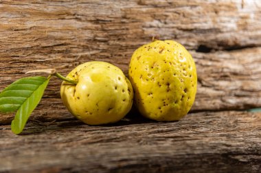 Tahta arka planda izole edilmiş sarımsı pembe guava meyveleri. Tüketim için toplanmış yeşil yapraklı taze guavalar. Brezilya 'dan tropik meyveler. Ahşap dokular. guava yaprakları ve meyveler.