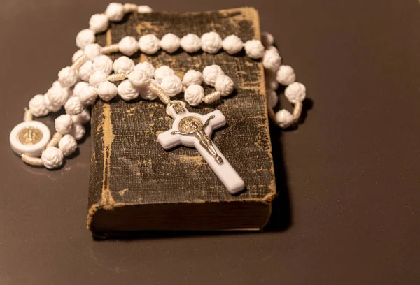 Old religious book. Symbols of Catholicism. Rosary and white crucifix. Symbol of veneration, which was initiated by Christians during the period after the crucifixion of Jesus Christ
