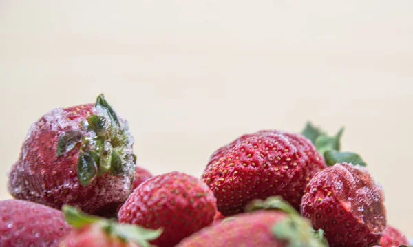 Frozen strawberries in close-up (Fragaria spp). frozen strawberries background. Fresh fruits covered with ice. Fruits arranged on a light background.