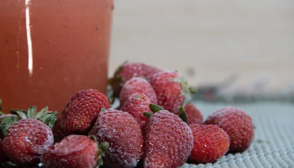 Frozen strawberries. Fresh red fruits. Glass of strawberry juice. Fragaria spp. Fruit consumed naturally. Ingredient for jellies, sweets, juices and medicinal and cosmetic use.