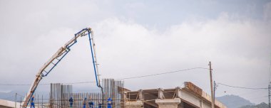 Güvenlik ekipmanlı adamlar. İnşaat. Altyapı işe yarıyor. Beton kamyon ve vinç. Temeller ve mühendislik. Demir zırh. Yol mühendisliği ve inşaat.