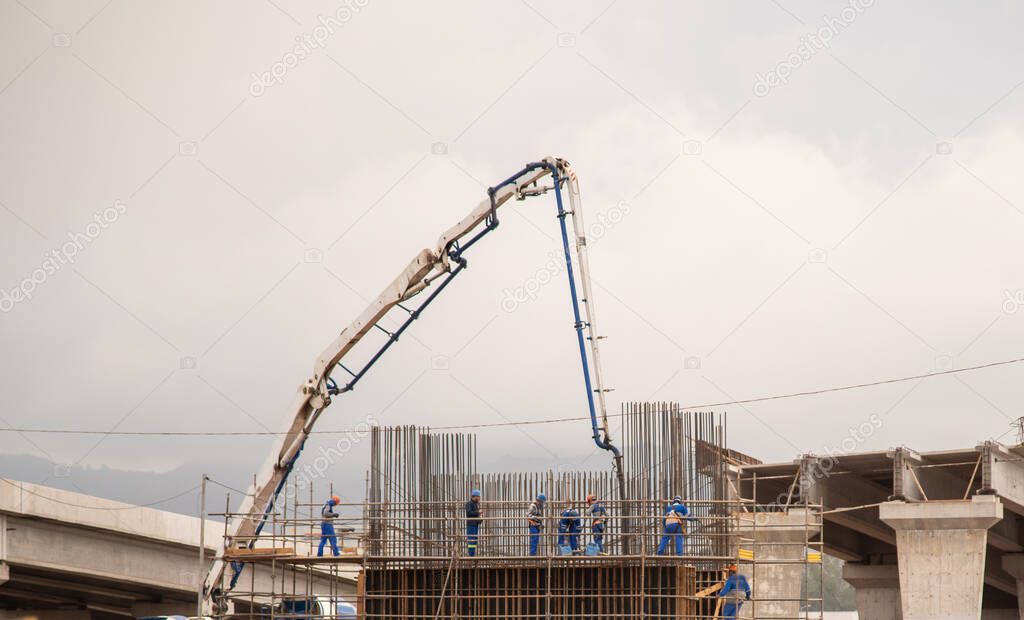 Men with safety equipment. Construction. Infrastructure works. Concrete truck and crane. Foundations and engineering. Iron armor. Road engineering and construction.