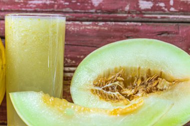 Kavun suyu. Tazeleyici içecek. Krink detoks ve antioksidan. Taze meyve. Yarım karpuz. Sarı meyveler. Kırmızı arka plan. Bayat ağaç. Tropik meyve suyu. Lifli yemek..