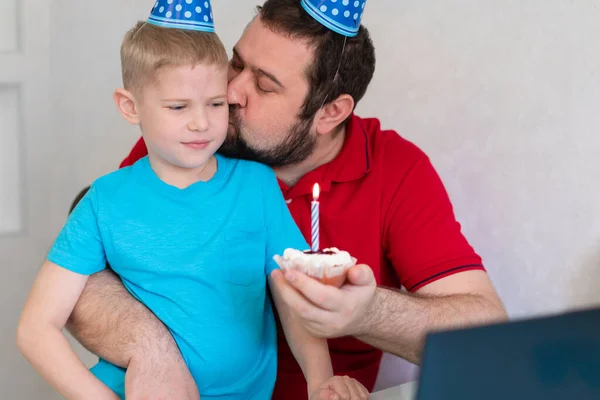 A kisfiú az apjával online ünnepli a születésnapját, jegyzetfüzetben beszél rokonaival és barátaival. — Stock Fotó
