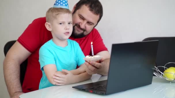 Malý chlapec se svým otcem slaví narozeniny na internetu, mluví prostřednictvím notebooku s příbuznými a přáteli. Sfoukni tu svíčku. — Stock video