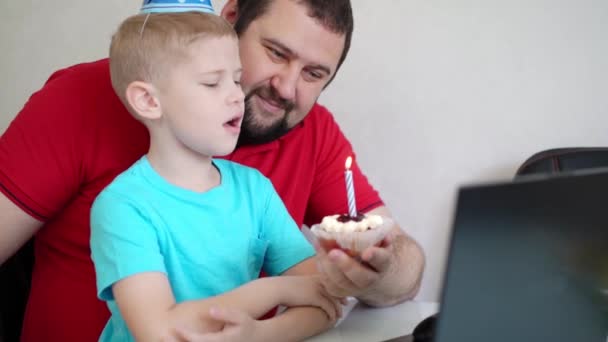 Malý chlapec se svým otcem slaví narozeniny na internetu, mluví prostřednictvím notebooku s příbuznými a přáteli. Sfoukni tu svíčku. — Stock video